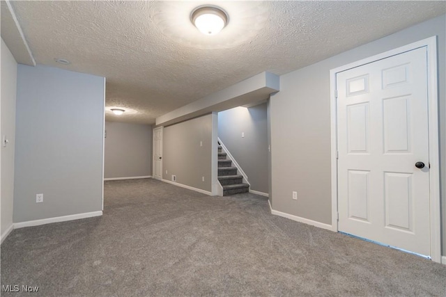 finished below grade area with carpet floors, a textured ceiling, baseboards, and stairs