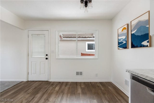 unfurnished dining area featuring dark wood-style flooring, visible vents, and baseboards