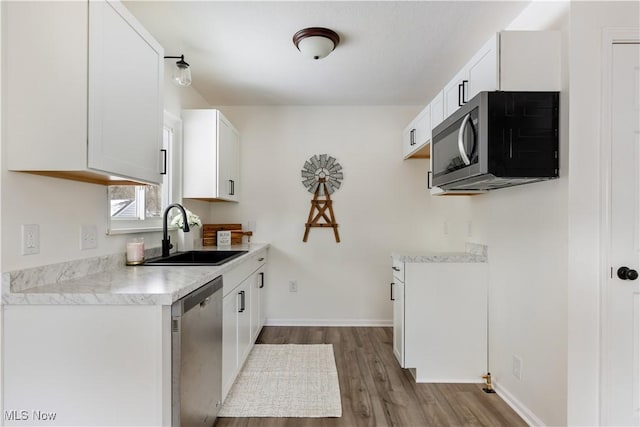 kitchen featuring white cabinets, stainless steel appliances, a sink, and light countertops