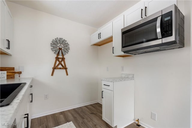 kitchen featuring white cabinets, stainless steel microwave, baseboards, and dark wood-style flooring