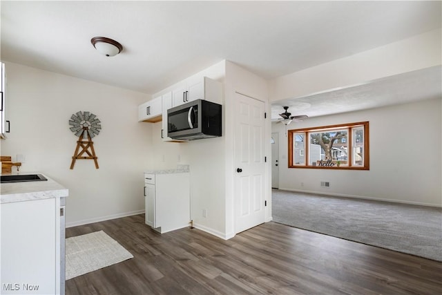 kitchen featuring dark wood finished floors, light countertops, stainless steel microwave, open floor plan, and white cabinetry