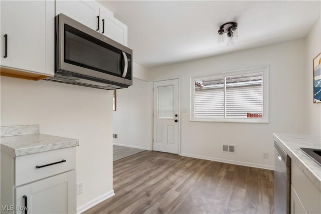 kitchen with light wood finished floors, light countertops, visible vents, appliances with stainless steel finishes, and white cabinetry