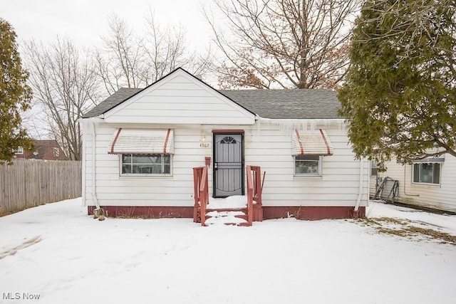 bungalow-style house featuring fence and roof with shingles