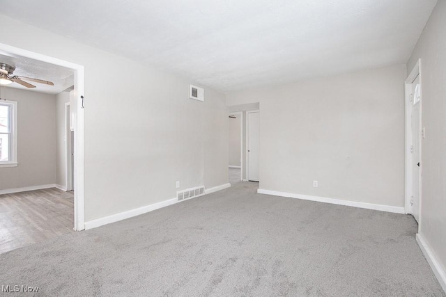 spare room featuring baseboards, visible vents, and light colored carpet