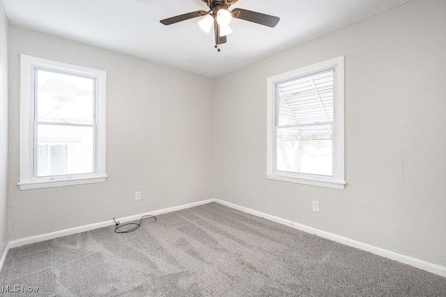 carpeted spare room featuring ceiling fan and baseboards