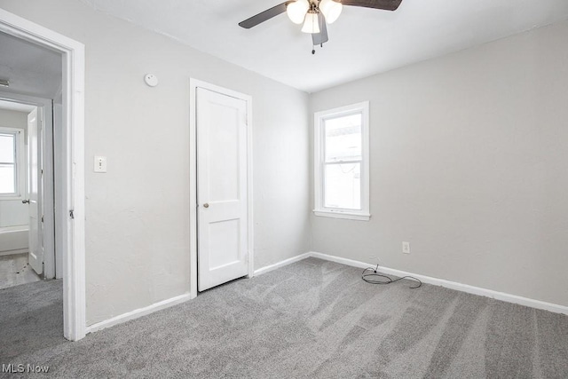 unfurnished bedroom featuring ceiling fan, carpet floors, multiple windows, and baseboards