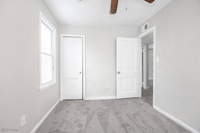 unfurnished bedroom featuring light carpet, a ceiling fan, visible vents, and baseboards