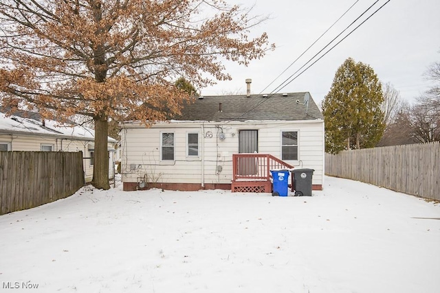 snow covered house with a fenced backyard