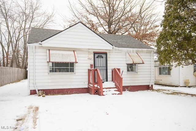 bungalow with a shingled roof and fence