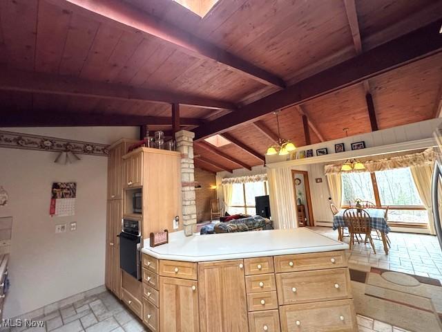 kitchen featuring lofted ceiling with skylight, decorative light fixtures, oven, light countertops, and stone tile flooring