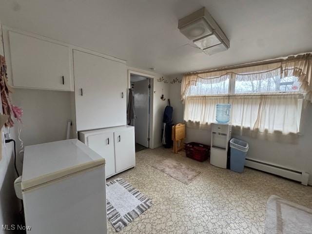 kitchen with white cabinets, fridge, baseboard heating, and light countertops