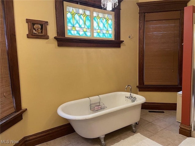 bathroom featuring a soaking tub, tile patterned flooring, and baseboards