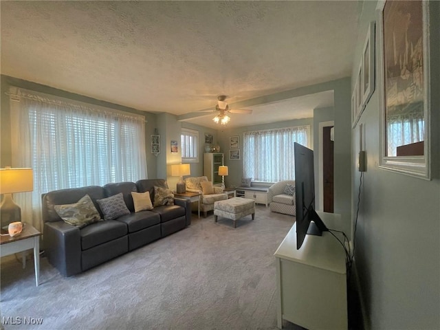 living area with a textured ceiling, carpet, and a ceiling fan