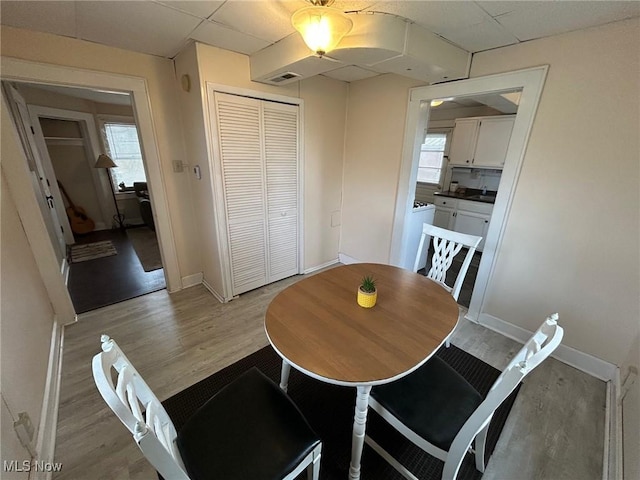 dining space featuring washing machine and clothes dryer, a paneled ceiling, visible vents, light wood-style flooring, and baseboards