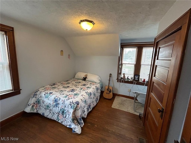 bedroom with visible vents, baseboards, dark wood-style flooring, vaulted ceiling, and a textured ceiling