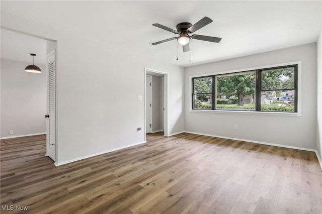 unfurnished room with dark wood-style floors, ceiling fan, and baseboards