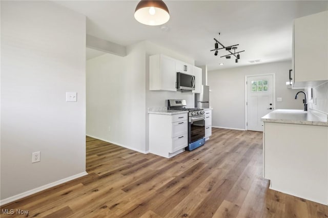 kitchen featuring a sink, white cabinetry, appliances with stainless steel finishes, and wood finished floors