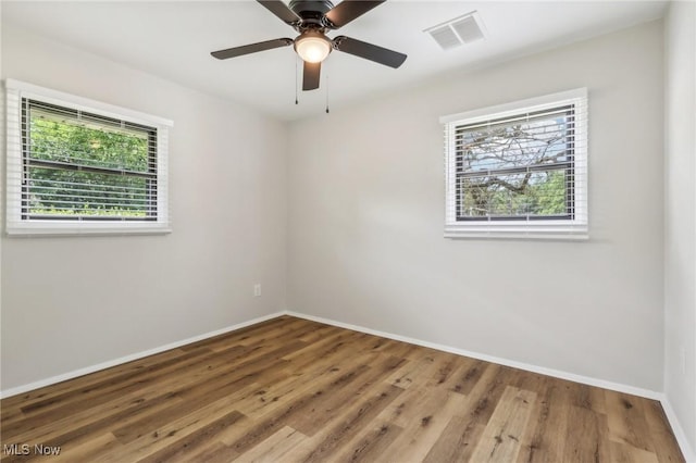 empty room featuring baseboards, visible vents, ceiling fan, and wood finished floors