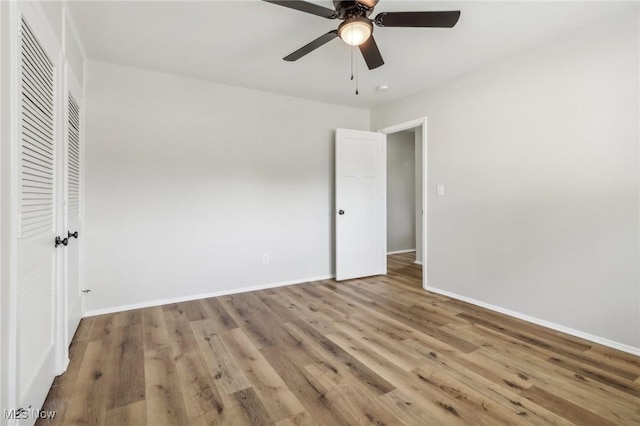 unfurnished bedroom featuring ceiling fan, a closet, light wood-style flooring, and baseboards