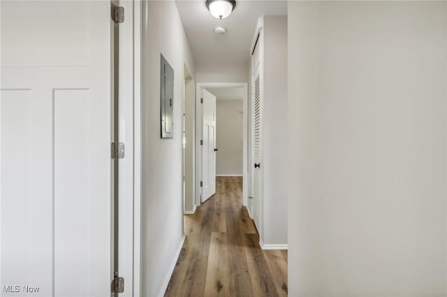 corridor with baseboards and wood finished floors