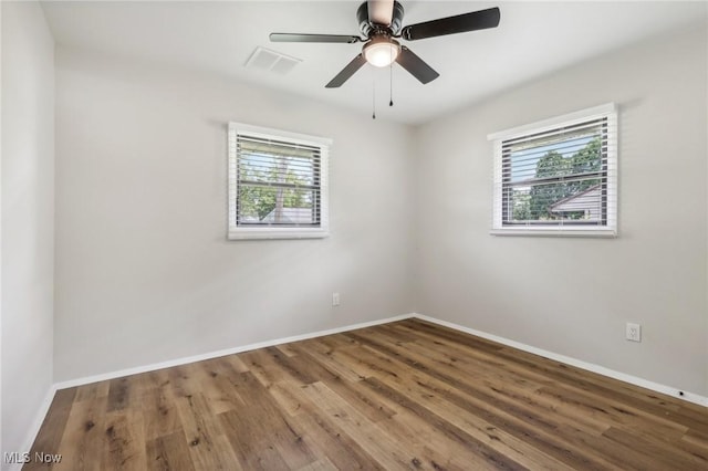 unfurnished room with plenty of natural light, visible vents, baseboards, and wood finished floors