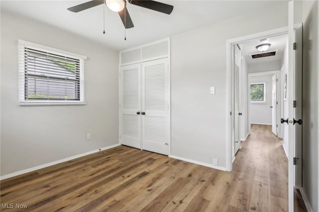 unfurnished bedroom with a ceiling fan, a closet, baseboards, and wood finished floors