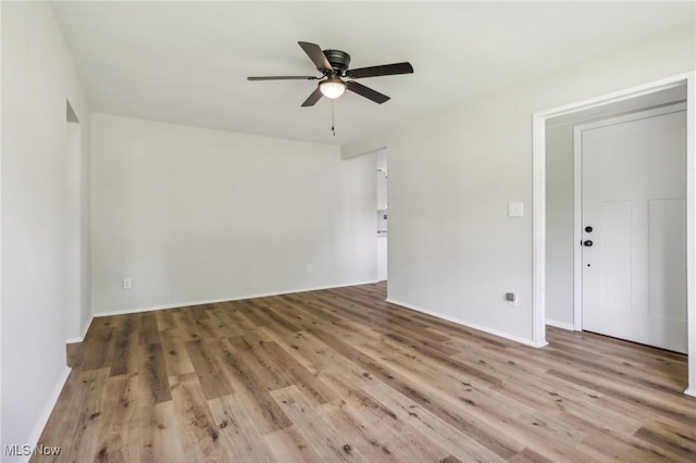 unfurnished room with light wood-type flooring, a ceiling fan, and baseboards