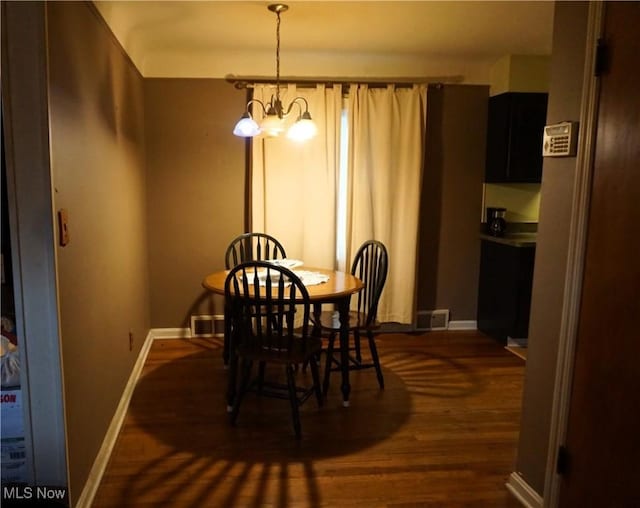 dining area featuring a chandelier, visible vents, dark wood finished floors, and baseboards