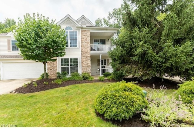 view of front of property featuring an attached garage, a balcony, concrete driveway, stone siding, and a front lawn