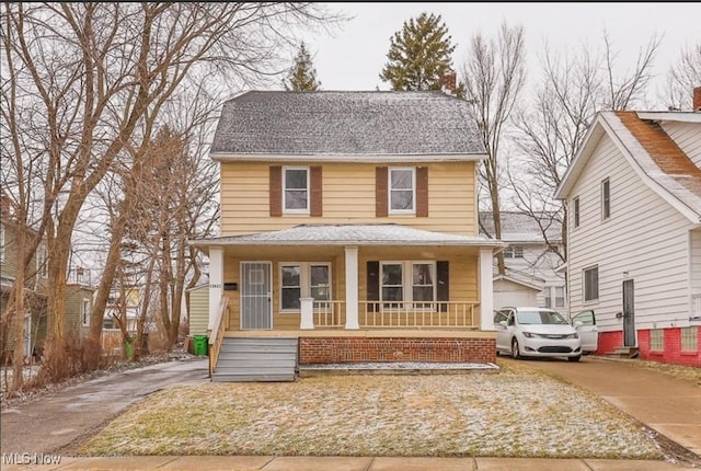 traditional style home with driveway, covered porch, a shingled roof, and a chimney