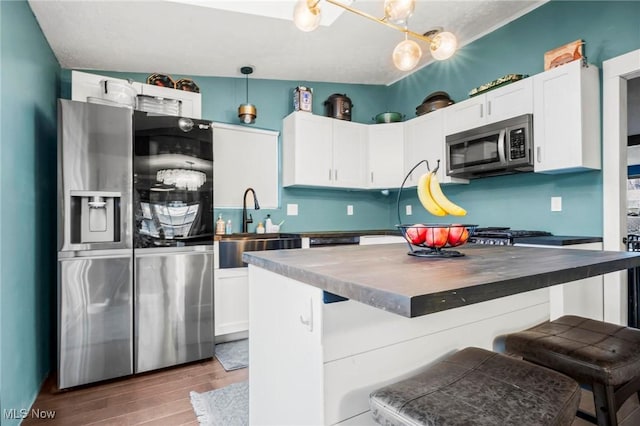 kitchen with appliances with stainless steel finishes, dark countertops, pendant lighting, and white cabinetry