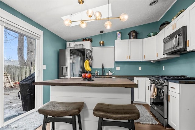 kitchen with butcher block counters, white cabinetry, a kitchen breakfast bar, appliances with stainless steel finishes, and pendant lighting