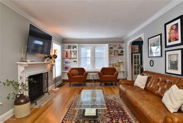 living room with light wood-style floors, baseboards, crown molding, and a fireplace with flush hearth