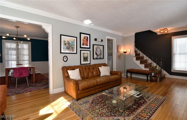 living room with baseboards, wood finished floors, stairs, a textured ceiling, and crown molding