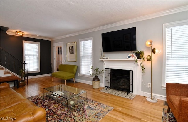 living area featuring stairs, wood finished floors, and crown molding