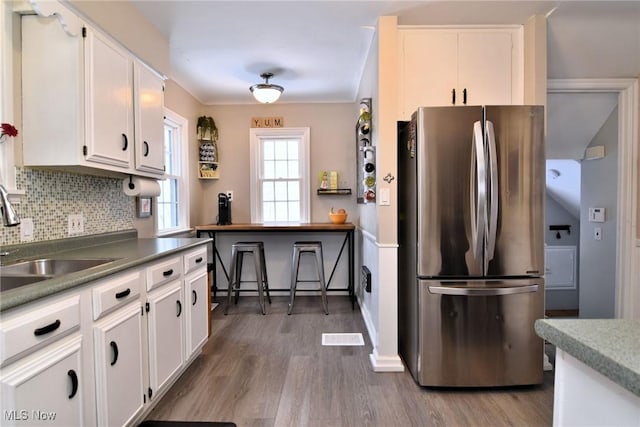 kitchen featuring decorative backsplash, a sink, freestanding refrigerator, and white cabinetry