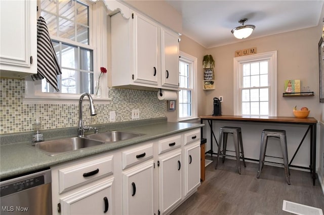 kitchen with a sink, visible vents, white cabinets, stainless steel dishwasher, and decorative backsplash