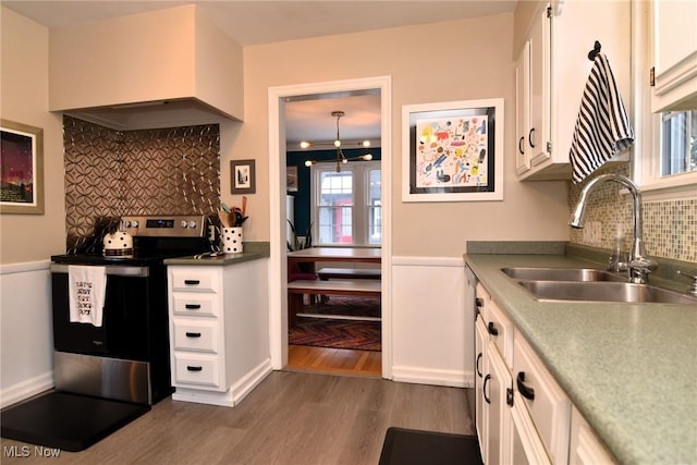 kitchen with dark wood finished floors, white cabinets, stainless steel electric range, light countertops, and a sink