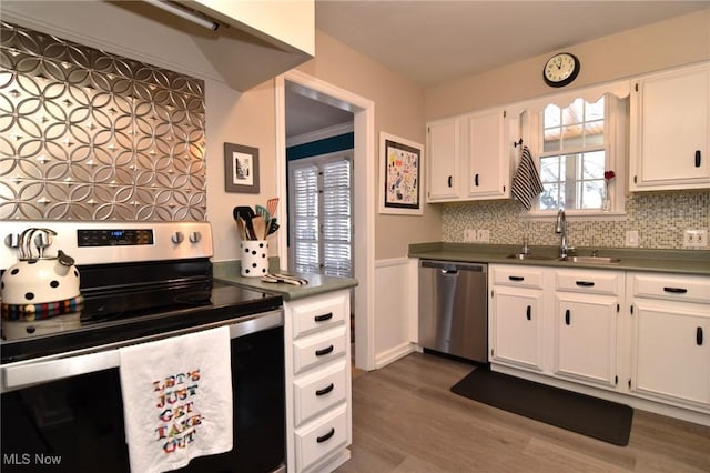 kitchen with white cabinets, dark countertops, stainless steel appliances, and a sink