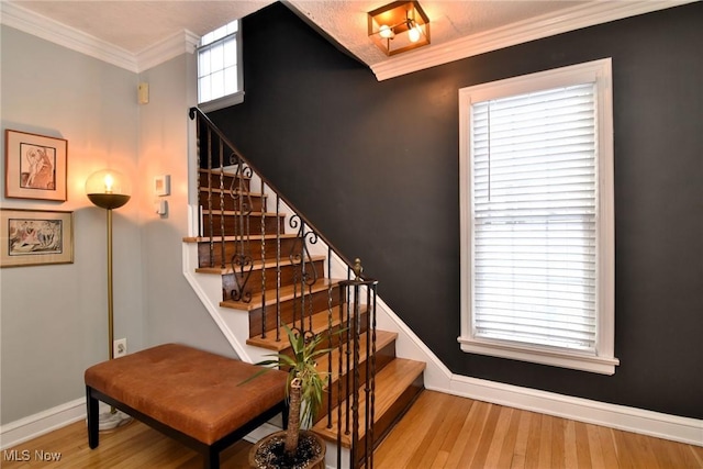 stairway with crown molding, baseboards, and wood finished floors