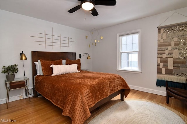 bedroom featuring a ceiling fan, baseboards, and wood finished floors