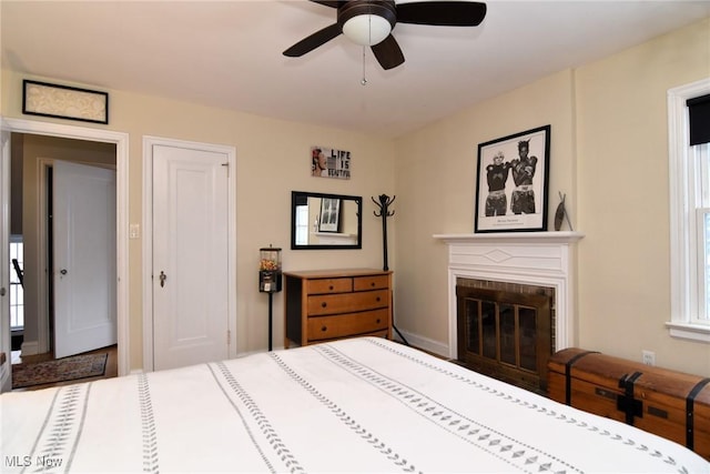 bedroom featuring a brick fireplace and a ceiling fan