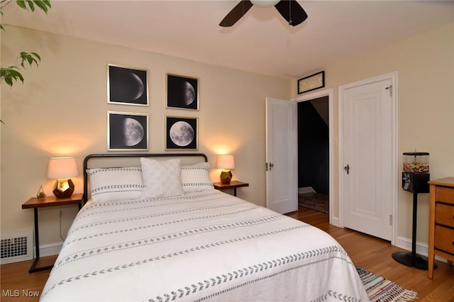 bedroom featuring baseboards, ceiling fan, visible vents, and wood finished floors