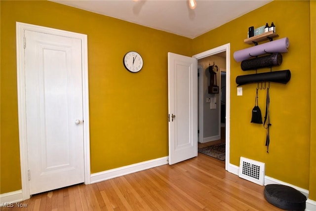 unfurnished bedroom featuring baseboards, visible vents, and wood finished floors