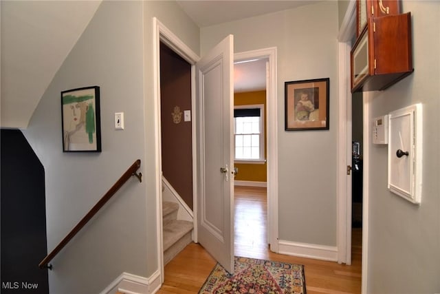 corridor featuring light wood-style floors, baseboards, and an upstairs landing