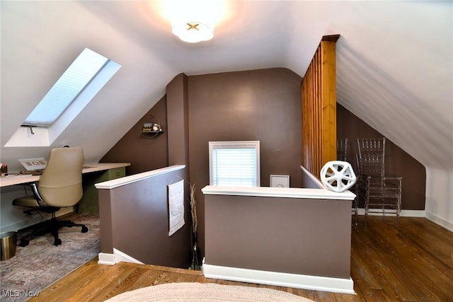 office area featuring lofted ceiling with skylight, dark wood finished floors, and baseboards