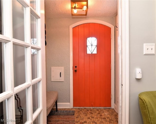 entryway featuring a textured wall and dark floors