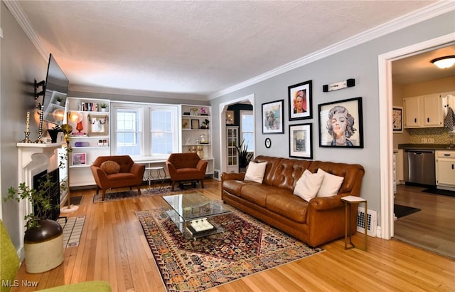 living area featuring ornamental molding, a fireplace, visible vents, and light wood-style floors