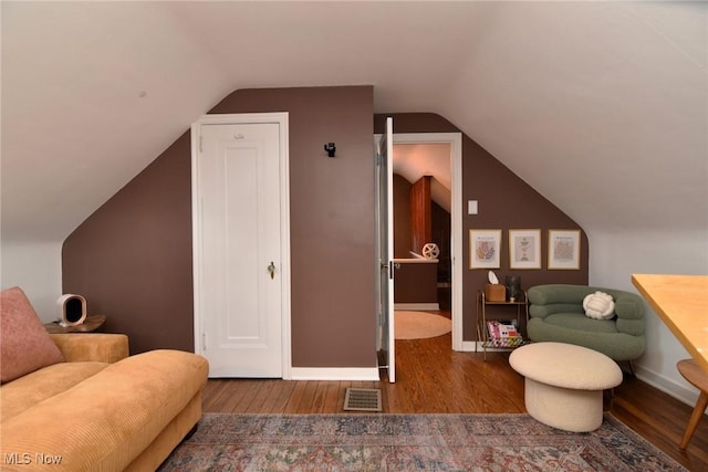 interior space with lofted ceiling, wood finished floors, visible vents, and baseboards