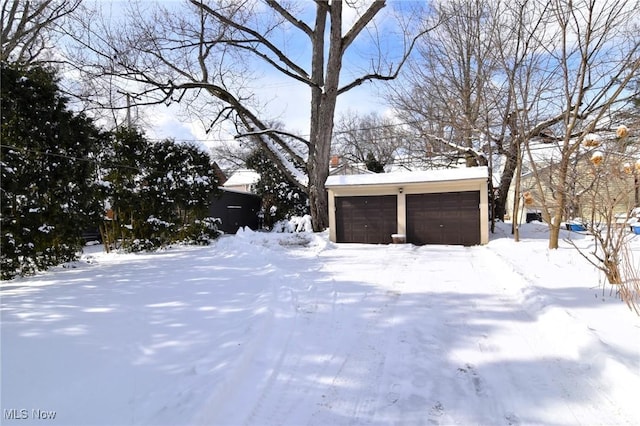 yard layered in snow featuring a detached garage and an outdoor structure